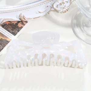 Macro shot of white iridescent acetate hair claw with golden Barrette La France text