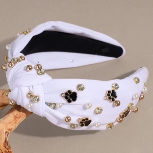 Detail showing white fabric knotted headband with pearls, rhinestones and cat claw charm