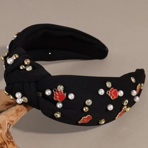 Detail of black knotted headband featuring pearls, rhinestones and red paw print charms