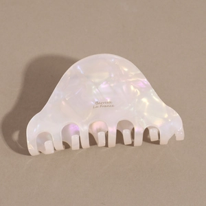 Detailed macro view of pearlescent marble acetate hair claw clip with golden lettering