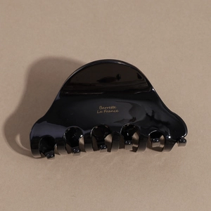 Detail of glossy black acetate hair claw clip featuring golden Barrette La France lettering