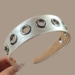 Detail of champagne gold satin headband with silver metal eyelets and anti-slip lining
