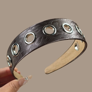 Macro shot of wide headband showing leopard texture and metallic silver eyelet detail