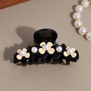 Detail of elegant French hair claw featuring resin flowers and white pearls decoration