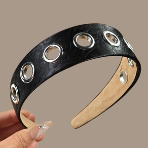 Detail of wide black textured headband featuring silver metal eyelets and soft lining