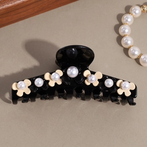Detail view of a French floral hair claw clip featuring elegant pearls and acrylic finish