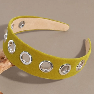 Gros plan d'un serre-tête en velours jaune moutarde avec œillets métalliques argentés