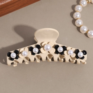 Detail of flower hair claw clip with pearls and cream finish on grey background