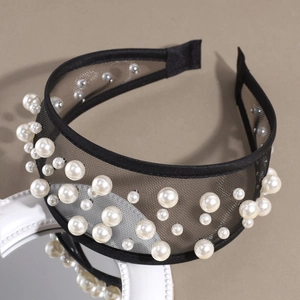 Detail showing white pearls on black mesh headband with elegant texture and light