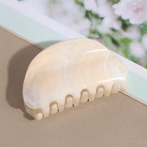 Detail of a large half-moon hair claw clip with cream marble texture and sturdy teeth