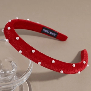 Close-up of red velvet headband with white pearls and hand-made woven label detail