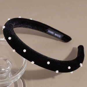 Detail view of handmade black velvet headband with elegant pearls and handmade woven label