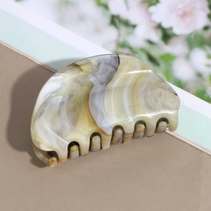 Detail of a semi-circular marble pattern hair claw with smooth acetate finish