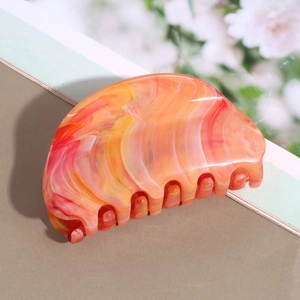 Detailed view of marble pattern hair claw clip with smooth teeth in orange and yellow