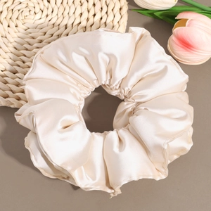 Detailed view of large cream satin scrunchie with soft silk texture and elegant pleats