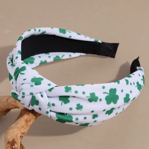 Close-up of white knotted headband with green shamrock and polka dot prints for St. Patrick's Day