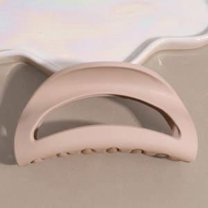 Detailed view of matte beige shark hair claw clip on an aesthetic pearl ceramic tray