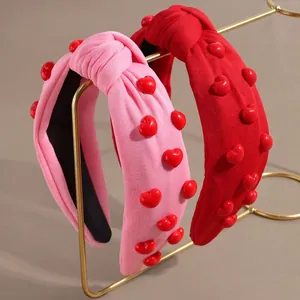 Pink and red knotted headbands with 3D heart decorations on golden display stands