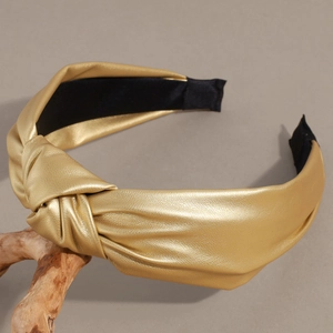Detail of champagne gold knotted leather headband with high-shine metallic finish