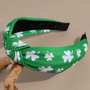 Detail of green St. Patrick's Day headband with white clover print on wooden branch