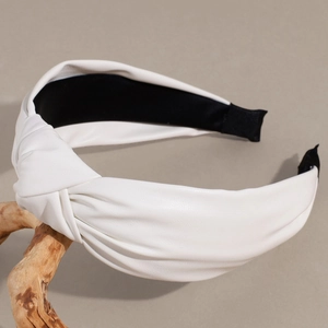 Close-up of a wide knotted white PU leather headband featuring textured surface detail