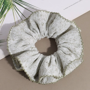 Detail of light green mesh hair scrunchie with contrasting dark green wavy edge stitching