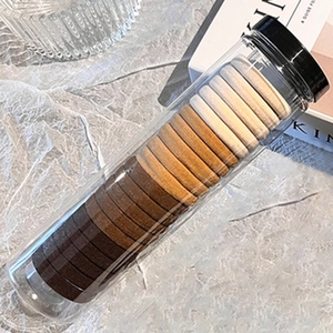 Détail d'élastiques à cheveux aux tons terreux dans un élégant récipient cylindrique