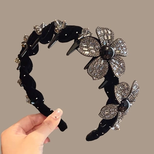 Detail view of black velvet headband with sparkling rhinestone flowers and inner teeth
