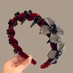 Detailed shot of burgundy velvet headband featuring rhinestone flowers and black beads