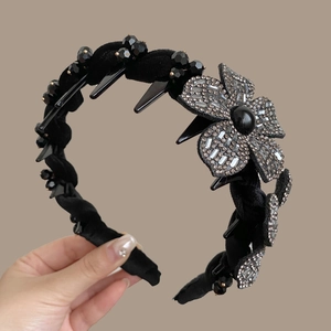 Close-up of black velvet headband with sparkling crystal flower and interior hair teeth