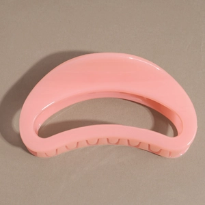 Gros plan sur une pince à cheveux rose en résine brillante au design demi-lune