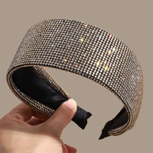 Close-up of sparkling rhinestone headband with wide black satin lining and gold gems