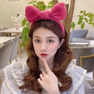 Detail of a bright rose pink lamb wool bow headband worn by a model in a cafe setting