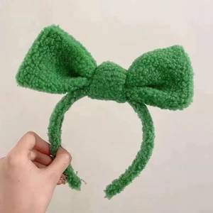 Detail of soft green plush lamb wool headband featuring a large fuzzy decorative bow