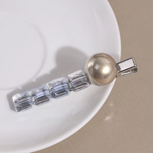 Vue macro d'une barrette à cheveux avec perles cristal et perle champagne sur céramique