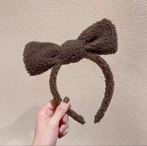 Detail of soft brown sherpa fleece headband featuring a large plush bow decoration
