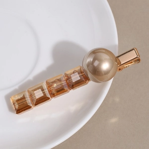 Vue macro de la pince à cheveux avec cristaux ambrés et perle de champagne