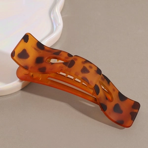 Macro detail of large leopard print hair claw clip with tortoise shell resin texture