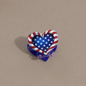 Detail of heart-shaped USA flag hair claw clip with blue glitter resin and clear teeth