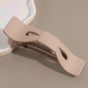 Macro view of matte beige large claw clip with internal teeth and sleek wave design