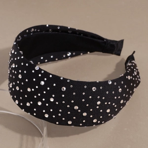 Close-up of sparkling crystals on a wide black fabric headband with star-like rhinestones