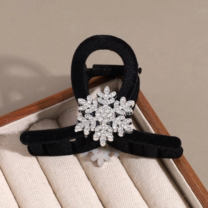 Dettaglio di una molletta per capelli in velluto nero con un fiocco di neve di strass