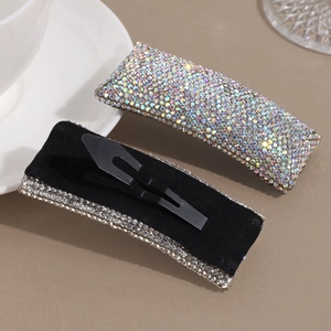 Elegant rectangle hair clip with colorful crystals and black velvet lining shown on a white tray