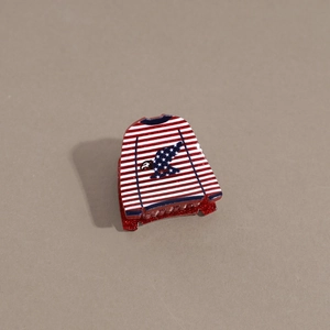 Detail of creative sweater-shaped hair claw with US flag eagle print and red glitter finish