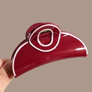Macro detail of wine red hair claw clip with golden glitter and white outlines