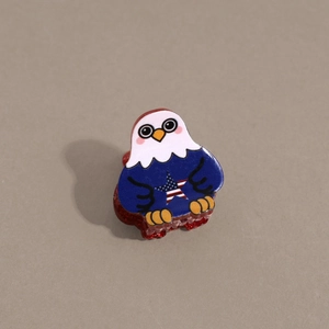 Detail shot of mini eagle hair claw clip with American flag pattern and red glitter teeth