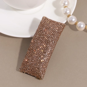 Detailed macro view of champagne rhinestone encrusted rectangular hairpin on neutral background
