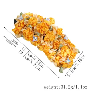 Detail view of large orange fabric flower hair clip with dimensions 13.5cm length