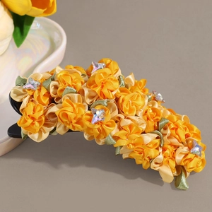 Detailed view of yellow fabric flower hair clip with rhinestones and satin petals