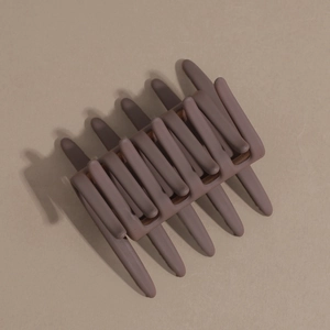 Detail view of large matte coffee hair claw clip with anti-slip teeth on beige background